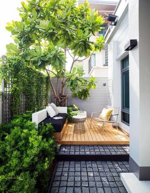a small contemporary backyard with a wooden deck, a built in daybed and a cool chair, some growing plants and a large living tree a small contemporary backyard with a wooden deck, a built-in daybed and a cool chair, some growing plants and a large living tree
