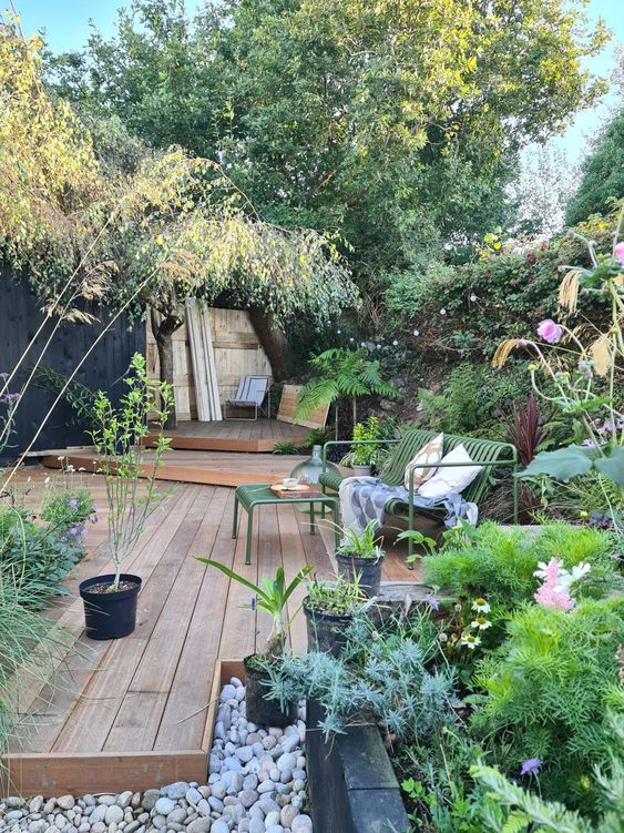 a lovely and welcoming garden with a raised wooden deck of several layers, greenery and blooms in raised garden beds a lovely and welcoming garden with a raised wooden deck of several layers, greenery and blooms in raised garden beds