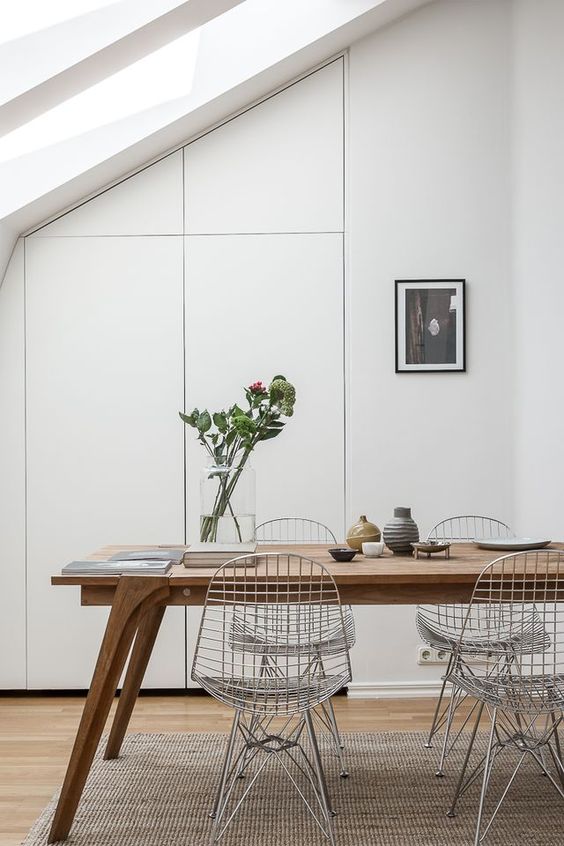 a Scandinavian dining space with skylights, a stained table, Eames wire chairs, some decor and an artwork