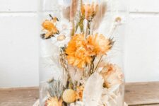 a bold dried flower arrangement in a cloche, with orange and neutral dried blooms, herbs and a bit of greenery is a cool centerpiece