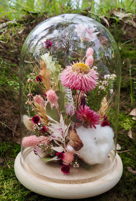a bright and fresh floral dome with cotton, pink dried blooms, burgundy ones, grasses and leaves is an amazing summer decoration
