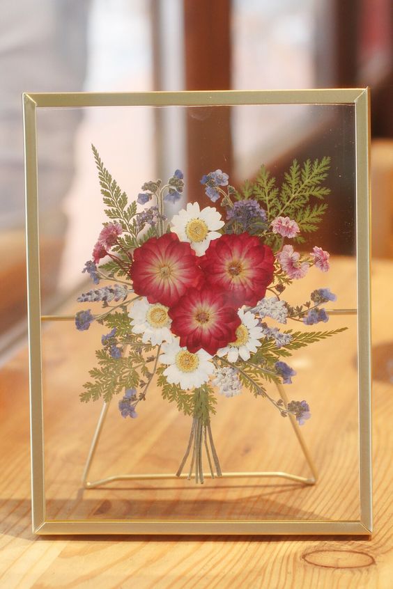 a bright pressed flower bouquet in a gilded frame is a lovely decoration that will add color, it's a fresh take on a usual arrangement