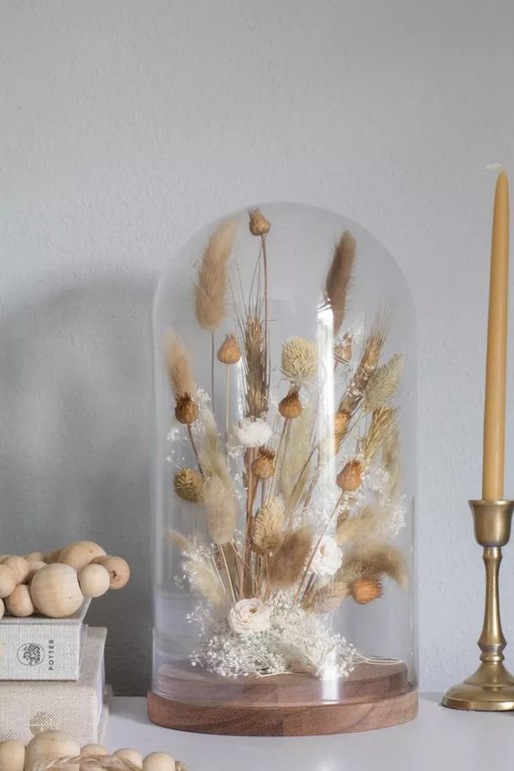 a cloche with a simple dried grass arrangement and seed pods is a cool boho or rustic decor idea that will soften any home decor