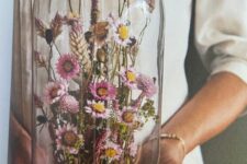 a cloche with a wooden base and an arrangement of beautiful pink dried blooms and grasses is a lovely idea for a boho wedding