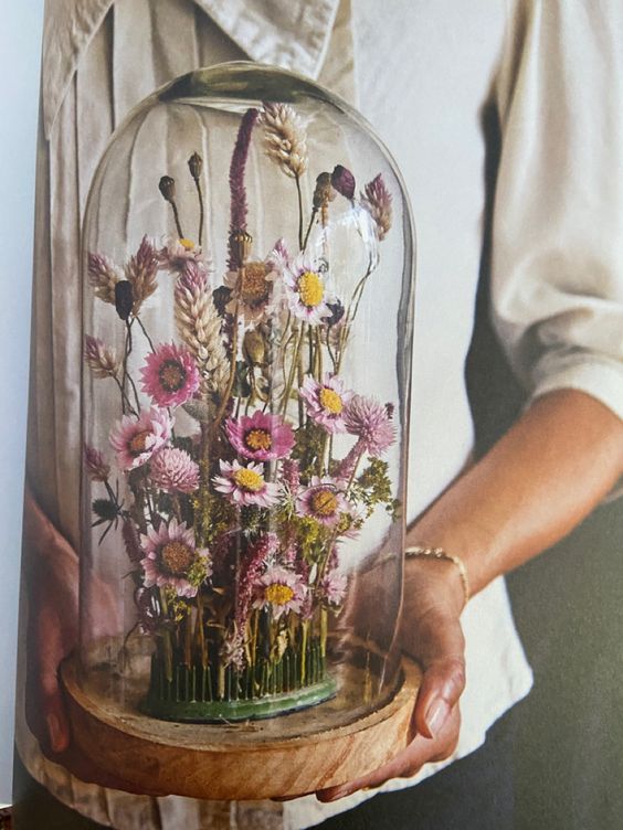 a cloche with a wooden base and an arrangement of beautiful pink dried blooms and grasses is a lovely idea for a boho wedding