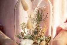 a cloche with a wooden tray, cotton, greenery, grasses and some neutral blooms and thistles is a great decoration for summer