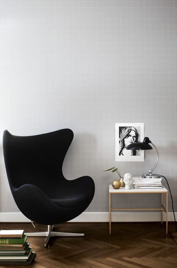 a cool nook with a black velvet Egg chair, a side table, books, decor and a table lamp is a chic and lovely space