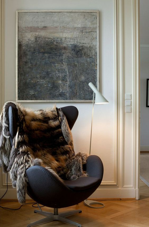 a cozy nook with an oversized artwork, a black Egg chair, a faux fur cover and a white floor lamp is cool for realxing