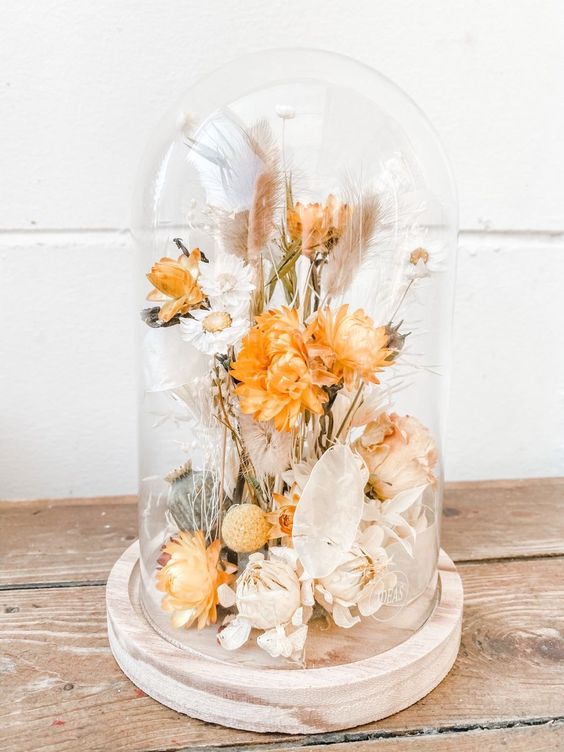 a dried flower dome with neutral and rust colored dried blooms, leaves, seed pods is a cool decoration for homes