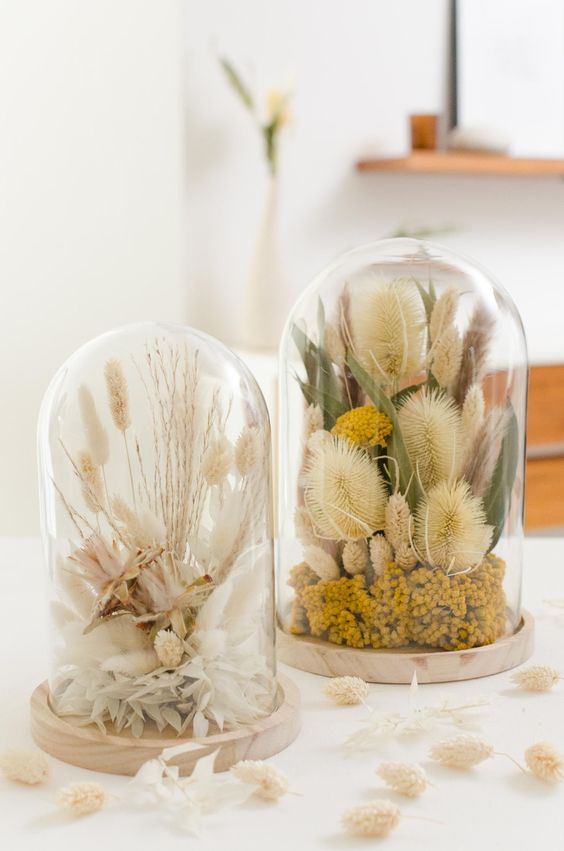 a duo of cloches with dried blooms, grasses, branches and leaves and some berries done in natural colors looks amazing