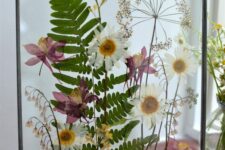 a fern, daisy and chamomile pressed flower frame in black, with chain is a chic and stylish idea for a boho space