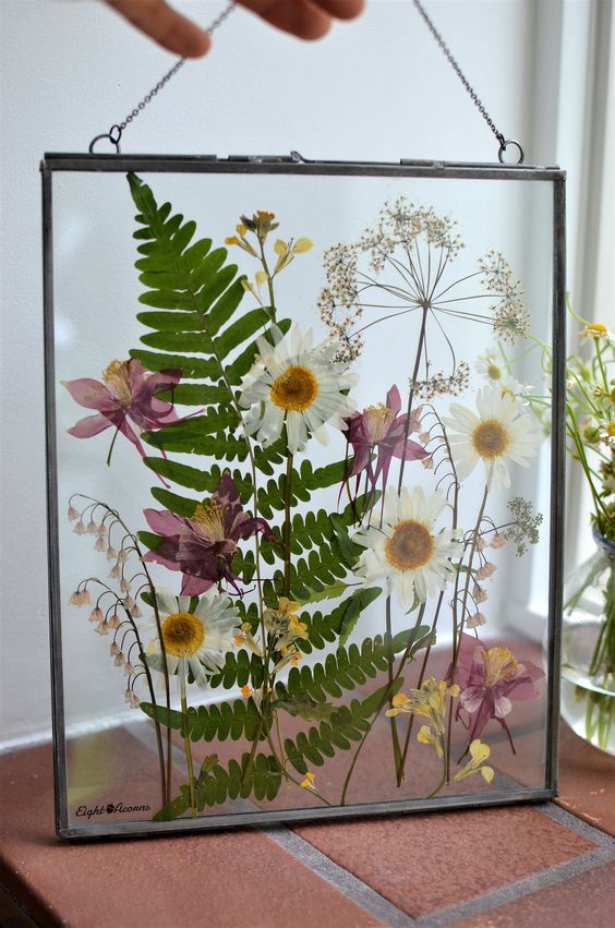 a fern, daisy and chamomile pressed flower frame in black, with chain is a chic and stylish idea for a boho space