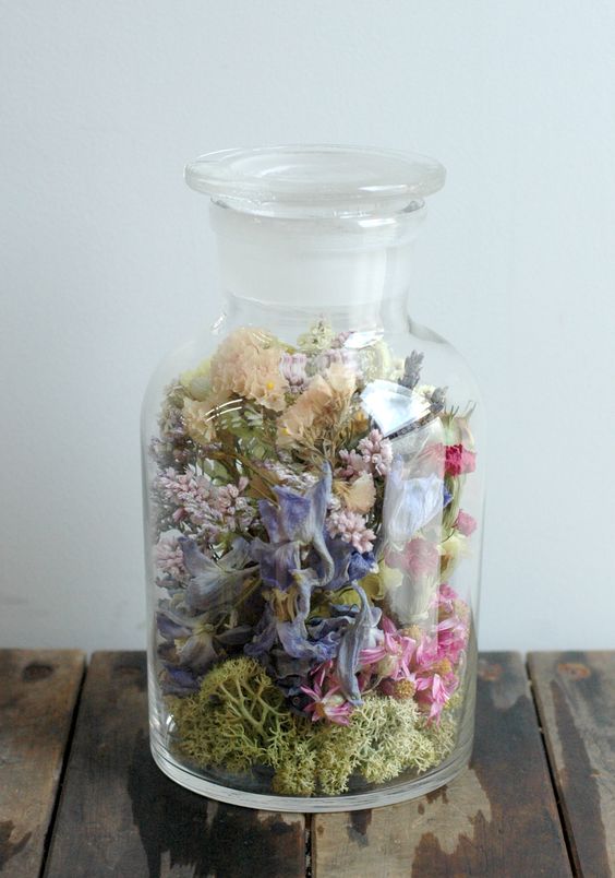 a glass bottle with moss and dried blooms and greenery is a creative decor idea for summer and not only, it's a lovely rustic decoration