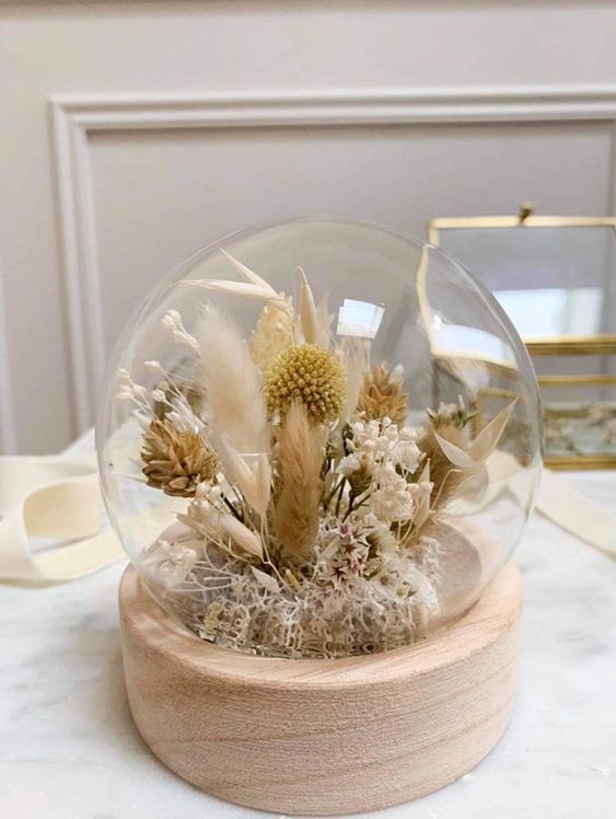 a globe with a wooden base and dried neutral blooms, dried grasses and billy balls plus some leaves is a chic boho decoration