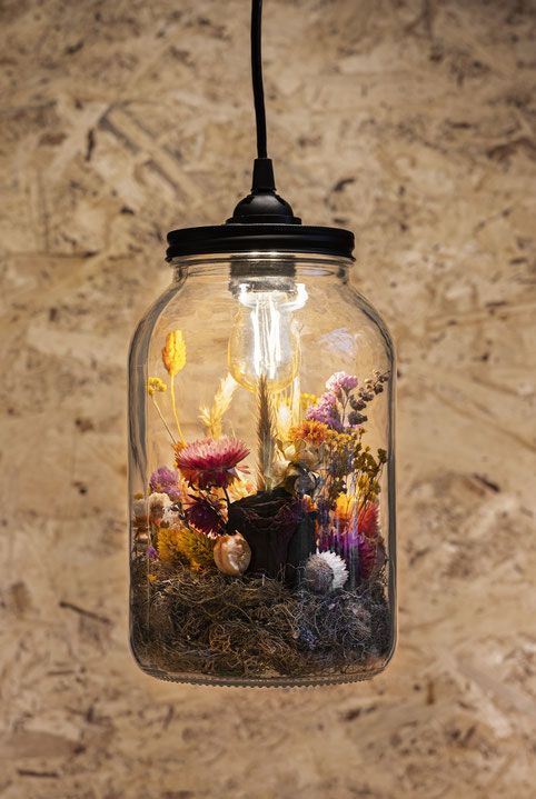 a jar that is a pendant lamp with a bulb and bold dried blooms in orange and pink plus some moss is a cool and bold idea