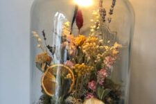 a jar with a black lid and a built-in bulb, with moss, dried blooms, grasses and fruit slices, feels and looks like summer for real
