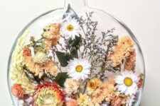 a large flat bottle filled with dried blooms of red, peachy pink and white color, with greenery and some grasses is a lovely summer decoration