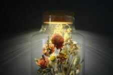 a large jar with a beautiful dried flower arrangement and grasses with a light built into the lid is a stylish and pretty idea