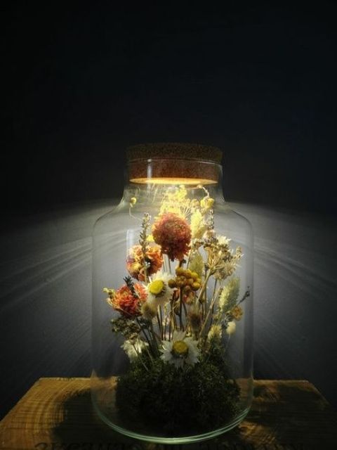 a large jar with a beautiful dried flower arrangement and grasses with a light built into the lid is a stylish and pretty idea