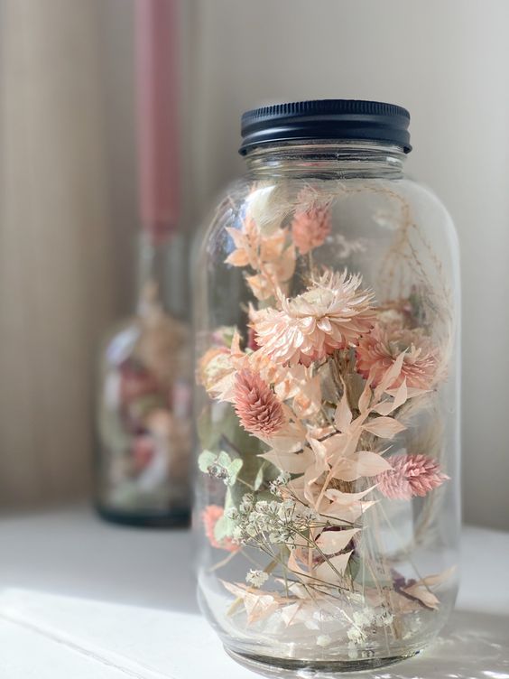 a large jar with pink and white dried blooms is a lovely decoration for a rustic or boho space, it looks airy and very chic