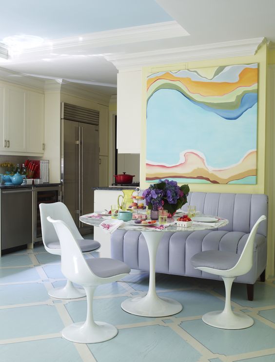 a pastel dining space with an oversized artwork, a lilac sofa, an oval table and lilac Tulips and bold blooms is a chic idea