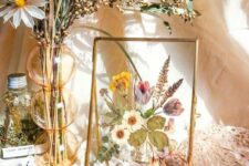 a pretty table art with pressed blooms and leaves in a gold frame is a stylish decoration for summer