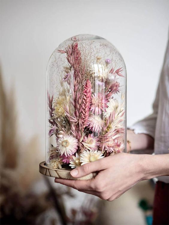 a small flower dome filled with pink and neutral dried blooms and grasses is a lovely spring or summer decoration