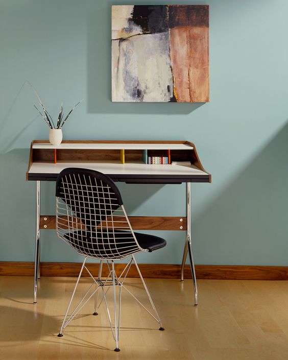 a small working space with a stained desk, an Eames wire chair with seat pads and an artwork is cute and lovely