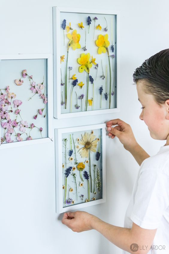 a stylish mini gallery wall with bright pressed flowers and leaves in white frames is a cool idea for any space