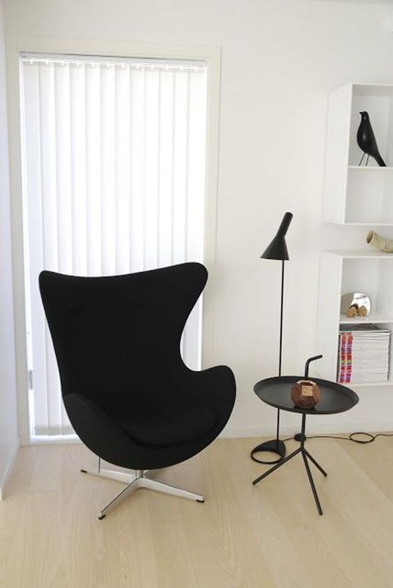 a stylish space with a black Egg chair, a side table, a floor lamp and some shelves is a cool and elegant space
