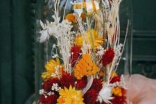 a super bold cloche arrangement of dried orange and burgundy blooms plus some neutral ones and grasses is an amazing idea for the fall