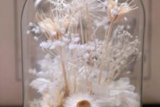 an airy and beautiful cloche filled with moss, dried white blooms and grasses is a stylish and pretty idea for a spring or summer space