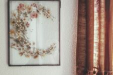 an arrangement of pressed wildflowers shaped as C in a black metal frame is a cool decoration to hang on the wall