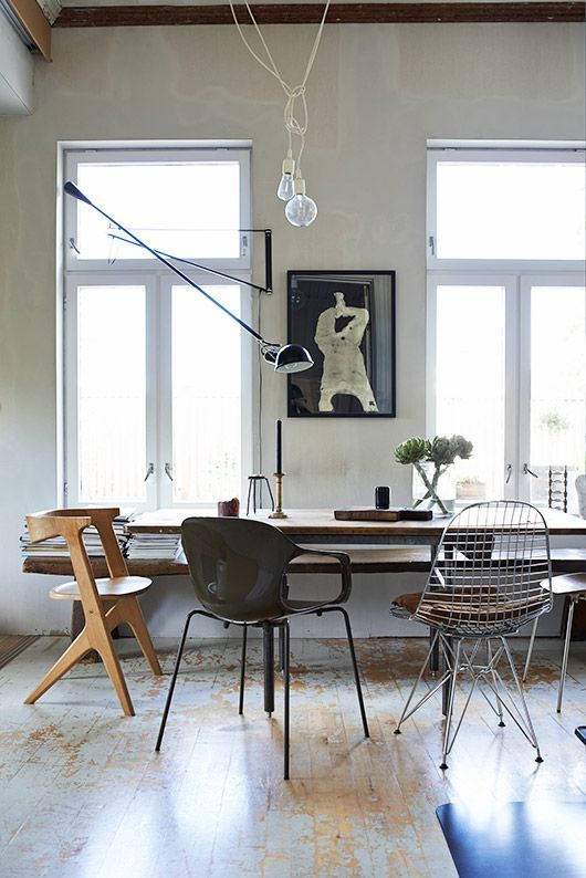 an eclectic dining space with a shabby chic floor, a stained able, mismatching chairs including Eames wire one, some art and lamps