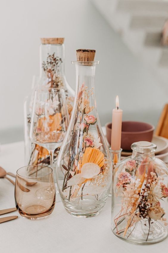 glass bottles of various designs filled with dried blooms, grasses and fronds are a cool arrangement for a rustic or boho space