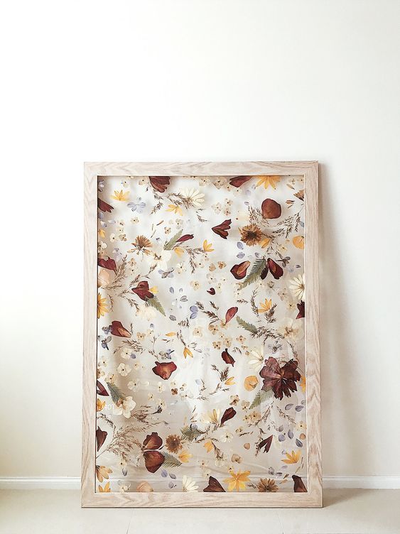 pressed neutral, mustard and burgundy blooms and leaves in a light-stained frame is a lovely decoration for the fall