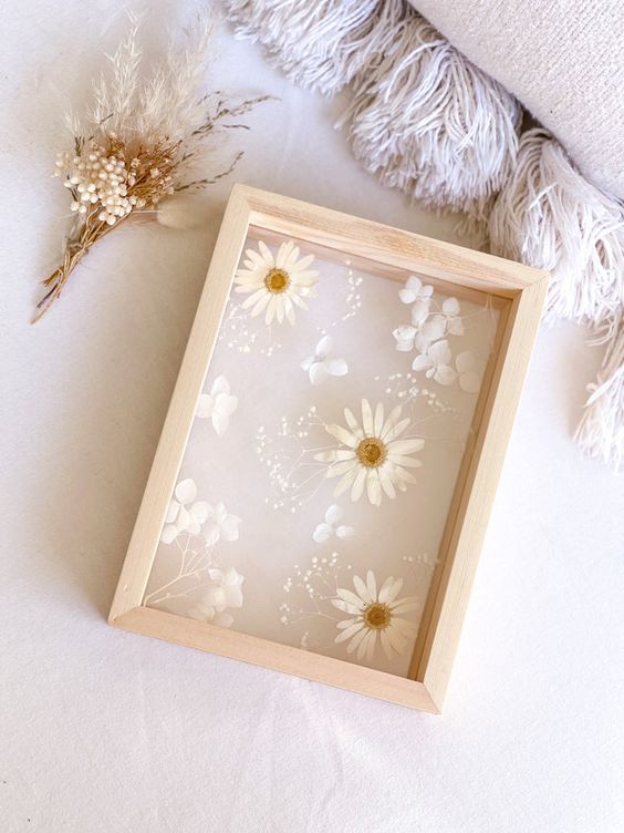 white blooms and petals in a light stained frame are a cool and ethereal decoration for any space