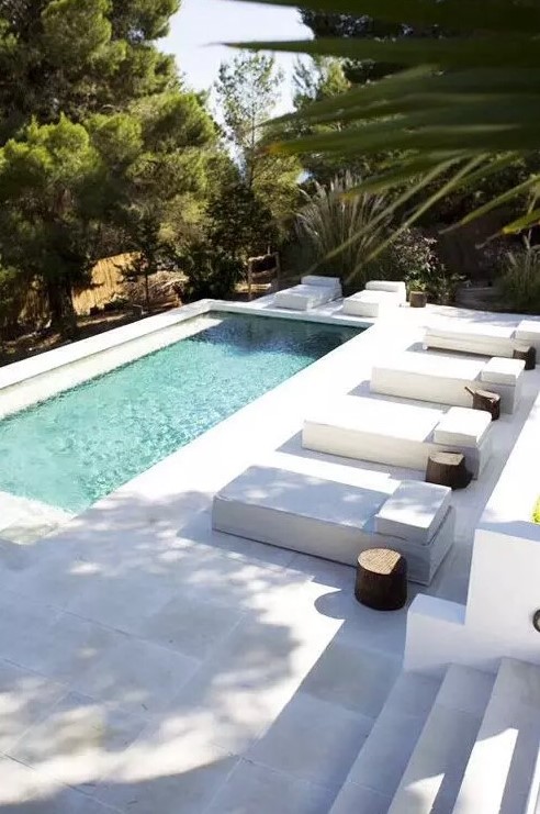 10-a-minimalist-backyard-with-a-pool-antislip-stone-tiles-that-form-a-deck-and-steps-a-series-of-loungers-with-stump-side-tables.jpg