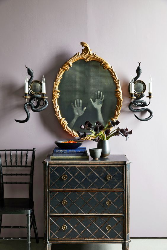 a gold frame mirror with ghost hands and snake decorated wall sconces are a cool combo for Halloween
