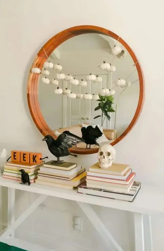 stylish minimalist Halloween decor with blackbirds, a skull and a garland of mini white pumpkins is very chic and cool