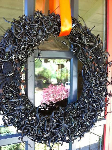 a black vine Halloween wreath covered with snakes, spiders and insects of all kinds is a lovely idea to style your front door