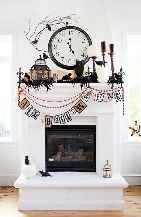 a whimsical Halloween mantel with feathers and blackbirds, white pumpkins, candles, a cage and beads and garlands