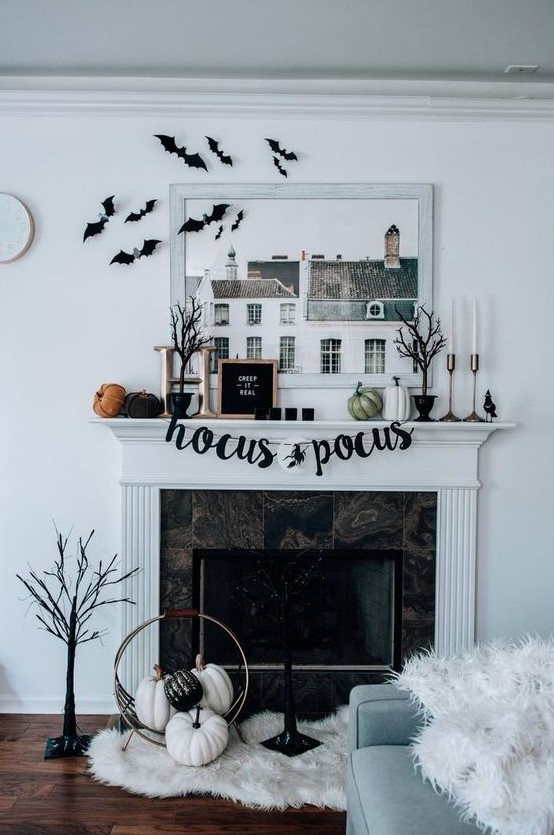 a stylish modern Halloween mantel with bats, pumpkins, signs, scary trees, candles and pumpkins on the floor
