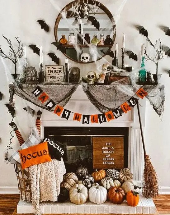 a colorful Halloween fireplace with a bold garland, lots of natural and faux pumpkins, printed pillows, black spider web, black bats on the wall