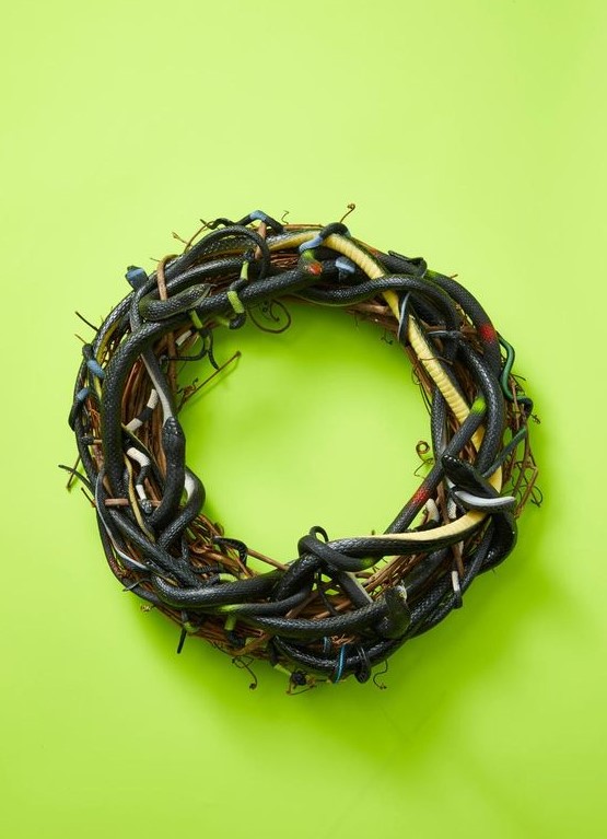 a scary Halloween wreath of vine interwoven with black and green faux snakes is a spooky and a veyr realistic decoration