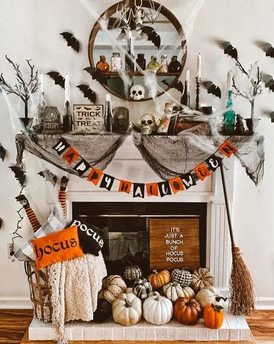 a colorful Halloween fireplace with a bold garland, lots of natural and faux pumpkins, printed pillows, black spider web, black bats on the wall