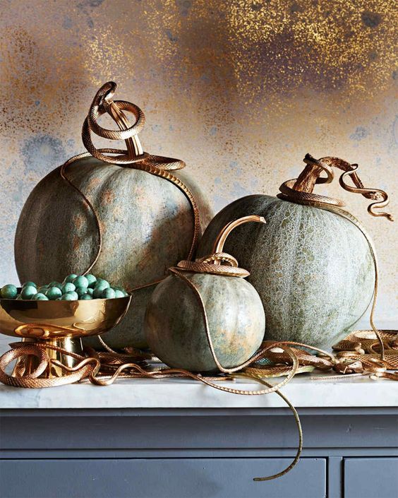 pumpkins topped with small gold resin snakes are a lovely decoration for Halloween