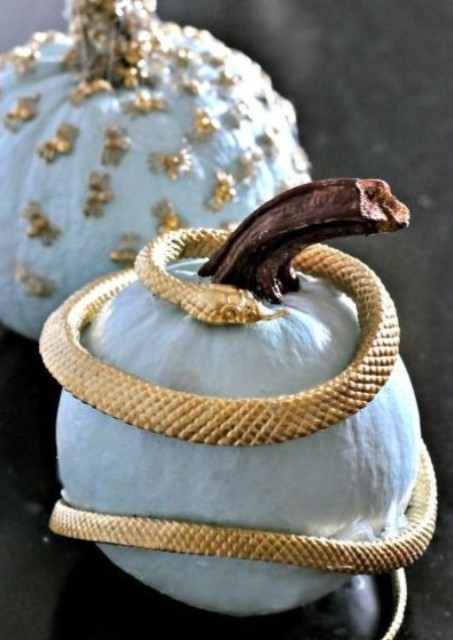 a pale blue pumpkin wrapped with a gold snake is a stylish and refined idea for your Halloween decor