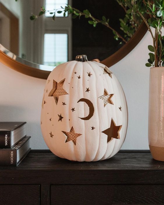 a white pumpkin with carved stars and moons is a creative idea for celestial Halloween decor