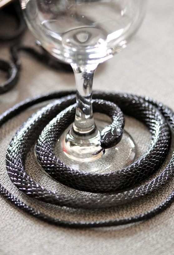 a black snake covering a glass is a lovely decor idea for styling your Halloween party table